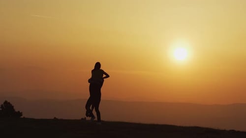 Romantic Couple Silhouette Embracing at Sunset Mountain Top