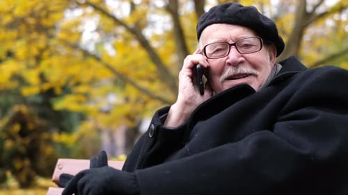 The Senior Communicates with Relatives on a Mobile Phone