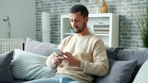 Man Relaxing at Home Using a Mobile Phone
