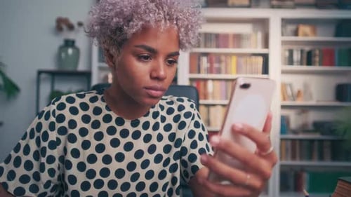 Happy Woman Reacts to Phone in Home Library