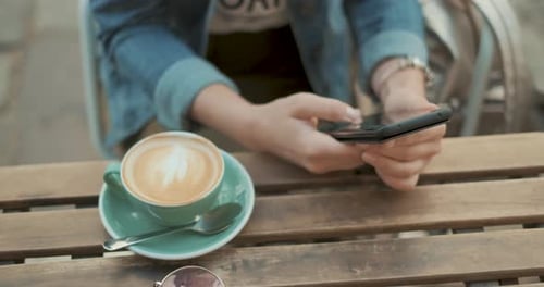 Hands of Young Woman Are Using Smartphone During Coffee Break in Cafe