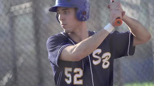 A young man practicing baseball at the batting cages.