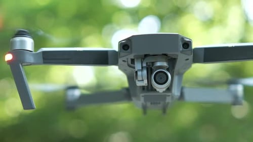 Drone copter with blurred propellers and video camera flying in air.