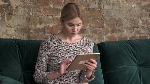 Woman Using Tablet on Green Sofa Indoors