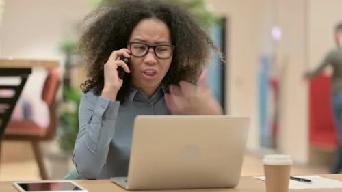 Stressed Woman on Phone at Desk With Laptop