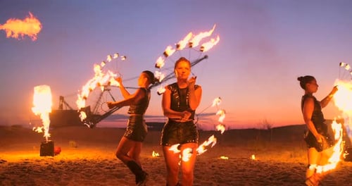 Feuershow Drei Frauen in ihren Händen drehen brennende Speere und Fächer im Sand mit einem Mann mit zwei