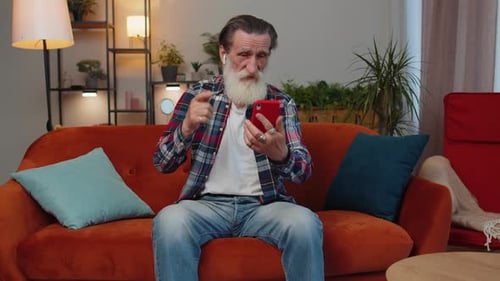Senior Man Video Calling at Home with Smartphone