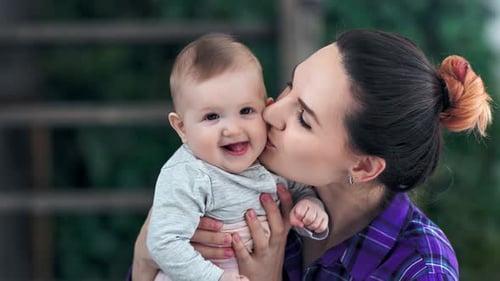 Gros plan, belle mère attentionnée, ayant de la tendresse, des sentiments d'amour, embrassant son petit bébé et souriant