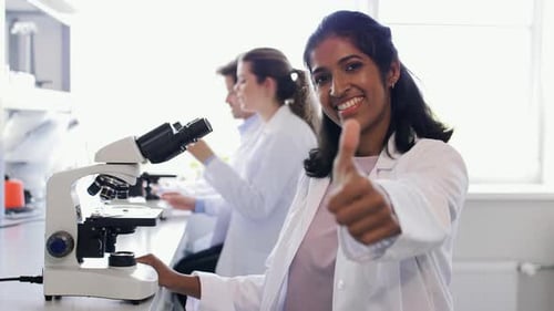 Scientist Smiling Next to Microscope in Laboratory