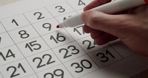 Man's Hand Write Down the 16Th Day on the Paper Calendar Using a Red Pen