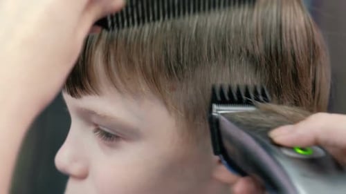 Child Getting Haircut with Electric Trimmer and Comb