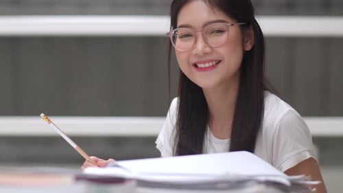 Female Student Writing in a Notebook, Smiling