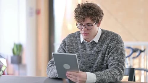 Young Man Celebrates Good News on Tablet