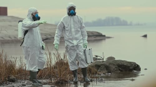Two Scientists Exploring Polluted River Bank