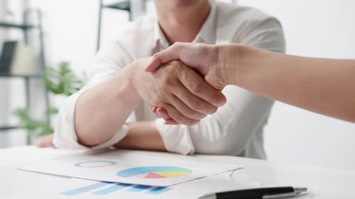 Creative people in casual wear discussing business shaking hands together while sitting in office