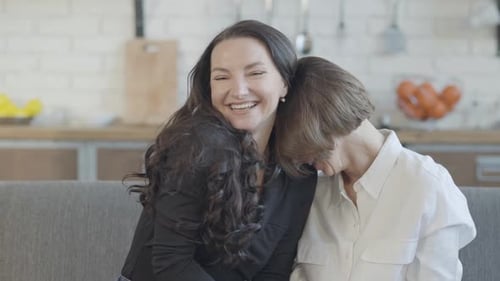 Two Women Laughing and Embracing on Sofa