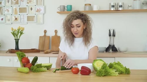 Woman Cutting Cucumber in Bright Kitchen