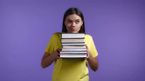 Smiling Woman As Student on Violet Background Holds Stack of University Books From Library