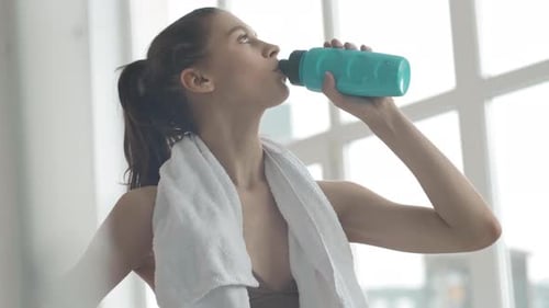 Young Woman Drinks Water After Workout