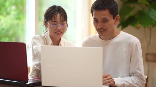 Young Adults Working Together on Laptops at Home
