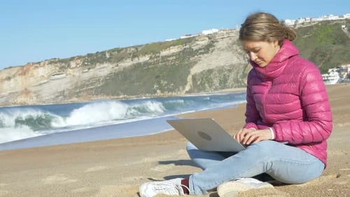Freelancer sitzt mit Laptop auf Ocean Beach Sand und funktioniert
