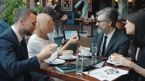Mature Business Lady Using Tablet During Negotiations with Business Partners in Restaurant