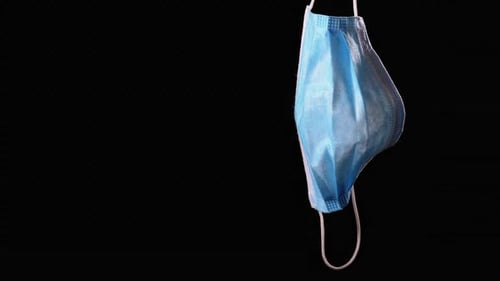 Clean Blue Face Mask Hanging Against Black Background