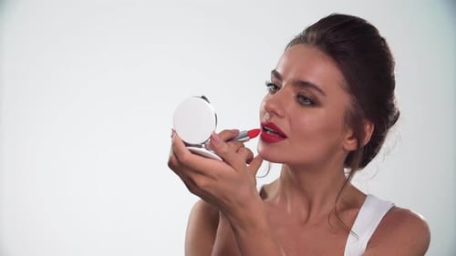 Woman Applies Red Lipstick in Studio Setting
