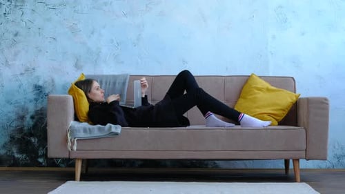 Woman Lying on Couch Using Tablet