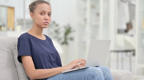 Young African Woman with Laptop Smiling at Camera in Cafe