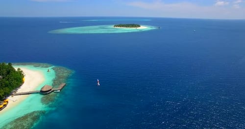 Aerial drone view of a man and woman sailing on a boat to a tropical island.