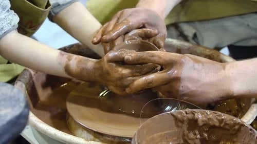 Child and Adult Hands Creating Pottery Together