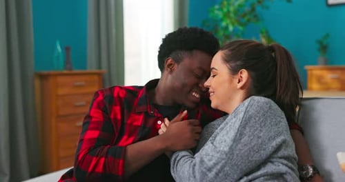 Loving Couple Holding Hands and Smiling on Sofa