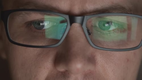 Man Wearing Glasses Reflecting Screen in Eyes