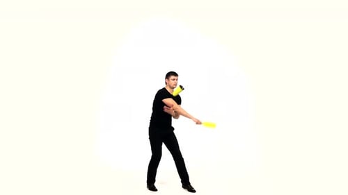 Man Juggling Yellow Objects in White Studio