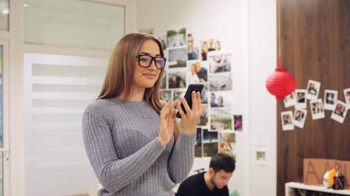 Young Woman in Glasses Use Smartphone in the Office. Text Message, Online Surfing, App, Social