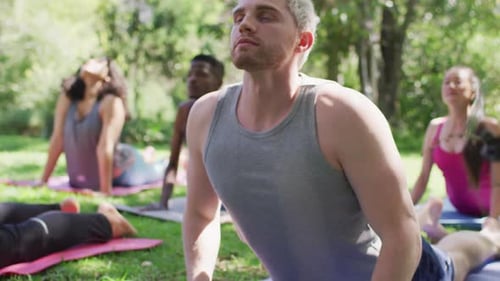 Group of diverse young people meditating and practicing yoga together at the park