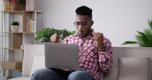 Man Celebrates Success on Laptop at Home