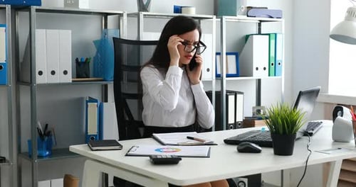 Businesswoman Talking on Smartphone and Working in Modern Office