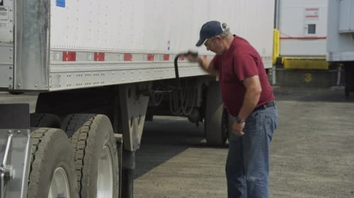 Man Inspecting Truck Landing Gear With Metal Tool