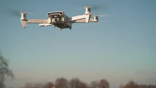White Drone Hanging in Air or Flying on Nature Background. Slow Motion Shot.