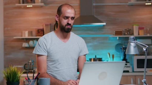 Man Video Calling at Kitchen Island with Laptop