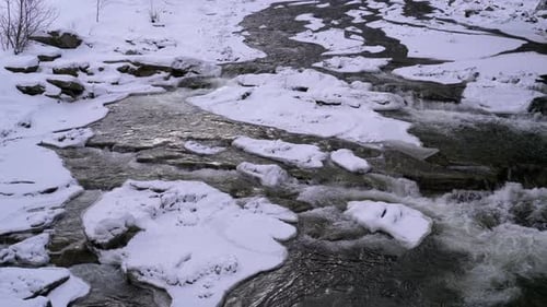 Mountain Stream in Winter. Mountain River Flowing Over Ice and Snow Near Rocks in Winter Landscape