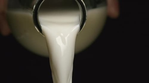 Milk Pouring from Glass Bottle in Close Up