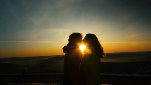 Romantic Couple Silhouette Embracing Against Golden Sunset Sky