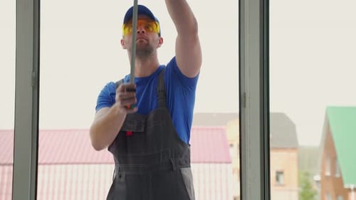 Construction Worker Measuring Window for Home Improvement