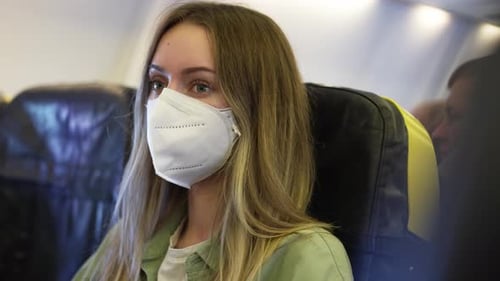 Woman wearing mask in airplane during flight