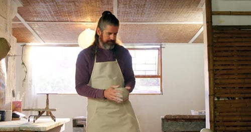 Male potter putting clay pottery wheel in pottery workshop