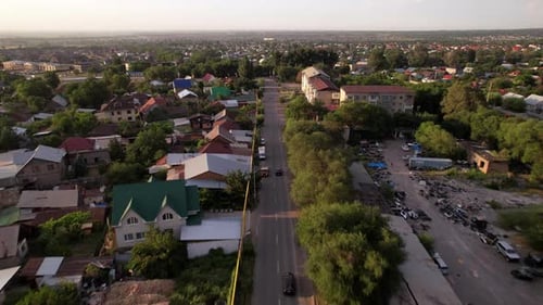 A Black Car is Driving on a Road in a Small Town