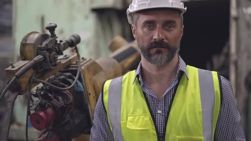 Bearded Engineer Standing by Machinery in Workplace